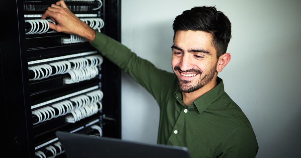 Website design and web hosting | What's the Connection | Laptop, maintenance and male technician in a server room for technical repairs by a control box.